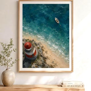 May include: A framed wall art print featuring an aerial view of a red and white lighthouse on a rocky coastline with a small white boat floating in the deep blue ocean water. The artwork displays textured brushstrokes and a coastal landscape scene.