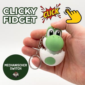 Puede incluir: Un llavero del personaje Yoshi en verde y blanco saliendo de un cascarón de huevo blanco. El texto CLICKY FIDGET aparece arriba a la izquierda, un icono de clic amarillo está arriba a la derecha y un círculo verde con el texto MECHANISCHER SWITCH está abajo.