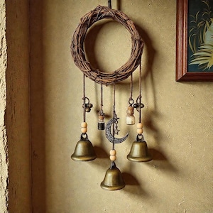 May include: A decorative wall hanging with a woven wreath, bronze bells, glass bottles, and a crescent moon charm. The bells hang from twine with wooden beads, creating a bohemian style. The color scheme is earthy tones, perfect for a rustic interior.
