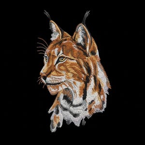 Pode incluir: Imagem bordada da cabeça de um lince em perfil, com costuras detalhadas em tons de castanho, bege e branco sobre um fundo preto liso. O lince tem orelhas pontudas e um olhar focado, capturando os traços do animal.
