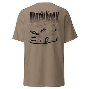 May include: A tan t-shirt featuring a black and white graphic of two rally hatchbacks. The word "RALLY" is above the word "HATCHBACK" in a distressed font. The shirt is a short-sleeved, crew neck style.