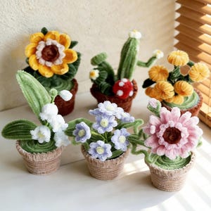 Peut inclure: Collection de six plantes en pot faites au crochet. Les plantes comprennent un tournesol, un cactus et diverses fleurs dans les tons de jaune, blanc, rose et bleu. Chaque plante est dans un petit pot marron.