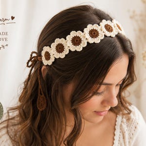 May include: A crochet headband featuring a row of connected flower motifs with cream-colored petals and dark brown centers. The accessory includes thin brown braided ties at the back for an adjustable fit. Text on the image reads Boho charm, HANDMADE WITH LOVE, and ADJUSTABLE FIT.