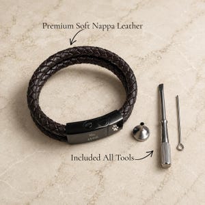 May include: A dark brown braided leather bracelet with a black metal clasp engraved with the text Max 4.9.2026 and a paw print icon. The set includes a small metal funnel, a flathead screwdriver, and a thin metal pin tool for maintenance.