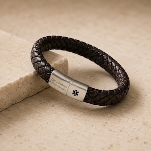 May include: A dark brown braided leather medical alert bracelet featuring a silver-toned metal clasp. The clasp is engraved with a black Star of Life symbol and the text: Type 2 Diabetes, ICE: 555-123-4567. The bracelet has a secure locking mechanism.