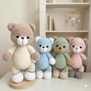 Könnte beinhalten: Vier handgefertigte Häkelteddybären in Pastellfarben: Beige, Hellblau, Grün und Rosa. Jeder Bär hat ein einzigartiges Farbschema mit weißen Akzenten auf den Pfoten und der Schnauze. Die Bären stehen aufrecht und präsentieren ihr weiches, strukturiertes Design.