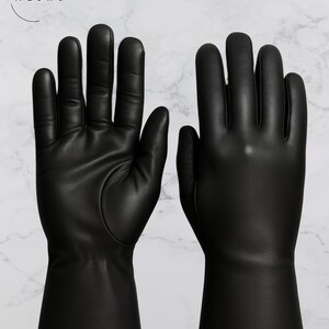 May include: A pair of black leather gloves with a smooth texture. The gloves have a long cuff and are displayed against a white marble background. The brand name "Crafts by Meshu" is in the upper left corner.