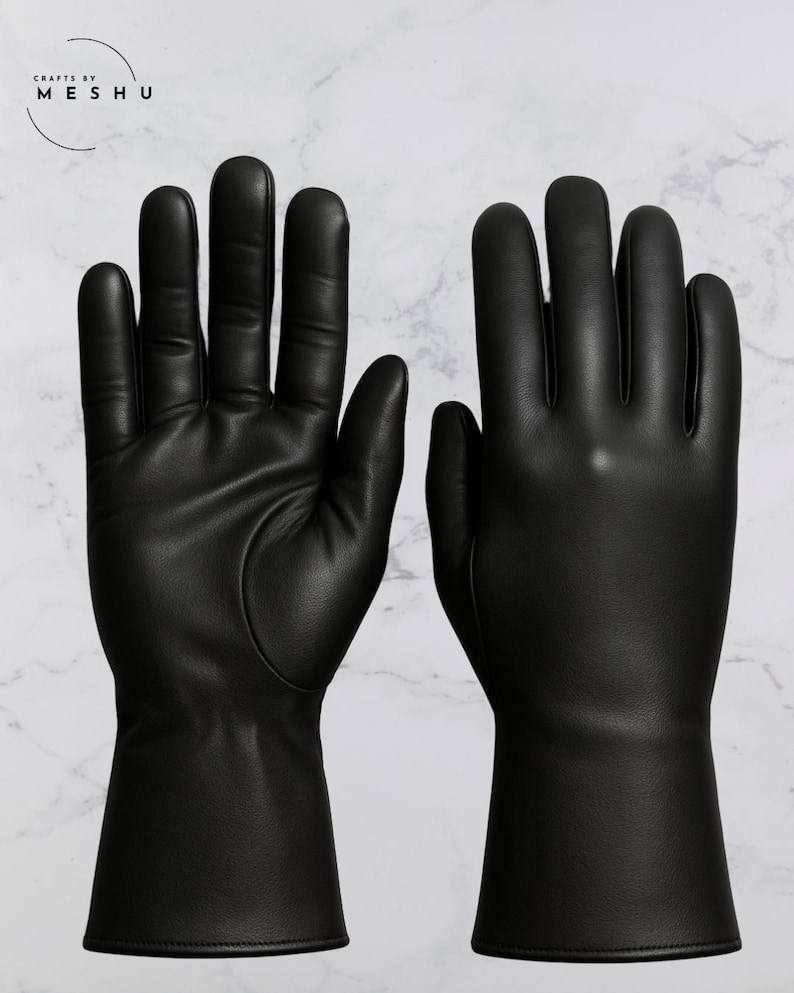 May include: A pair of black leather gloves with a smooth texture. The gloves have a long cuff and are displayed against a white marble background. The brand name "Crafts by Meshu" is in the upper left corner.