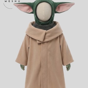 May include: A tan-colored child's coat with a large hood resembling a character from a popular science fiction franchise. The hood is green with large, pink-lined ears. The coat has a wide collar and long sleeves. The gloves and feet are green.
