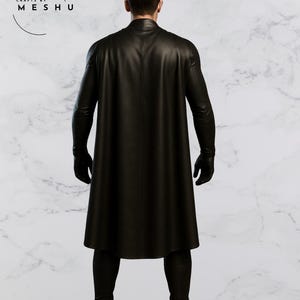 May include: A black leather coat with a cape, gloves, and boots. The coat is long and reaches the ankles. The image is taken from the back, showing the full outfit. The brand name "Crafts by Meshu" is visible in the upper left corner.
