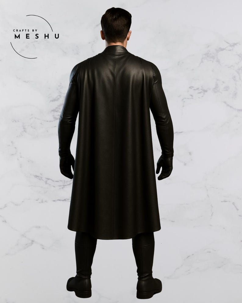 May include: A black leather coat with a cape, gloves, and boots. The coat is long and reaches the ankles. The image is taken from the back, showing the full outfit. The brand name "Crafts by Meshu" is visible in the upper left corner.