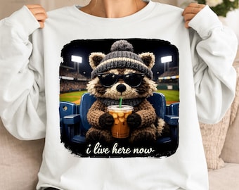 Vivo qui adesso Procione PNG, Procione in filato sintetico che beve caffè freddo, Campo da baseball divertente PNG, Clipart di softball, Maglietta da torneo di viaggio