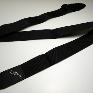 May include: Black guitar strap with a leather end and a silver guitar logo that says "Janz".
