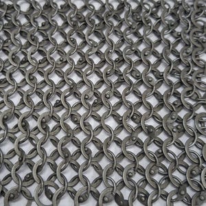 May include: Close-up of a section of chainmail armor. The interlocking metal rings are a dull silver color, creating a dense, flexible mesh. The pattern is a repeating series of connected rings, typical of historical armor.