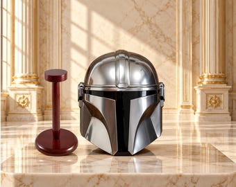 May include: A polished silver-colored helmet with a black visor and a central ridge, featuring a smooth metallic finish. Beside the helmet stands a dark reddish-brown wooden display stand with a circular base and a vertical support post.