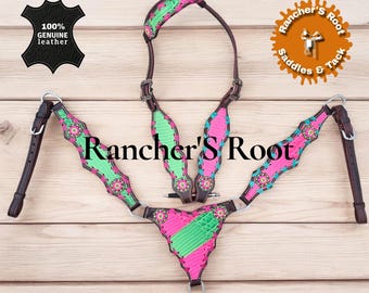 Puede incluir: Un juego de guarnicionería para caballos de cuero genuino con un diseño vibrante. El juego incluye un cabezal, un peto y riendas, con detalles en rosa y verde y detalles florales. El texto "Rancher's Root" es visible.