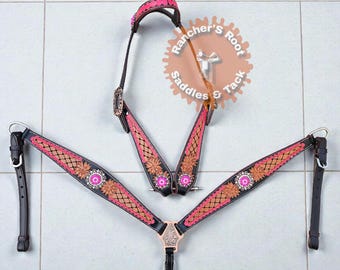 Puede incluir: Un juego de guarnicionería para caballos en negro y rosa con diseños florales y geométricos. El juego incluye un cabezal, un petral y riendas. La guarnicionería presenta detalles en rosa, marrón y plata, con una hebilla y conchos decorativos.
