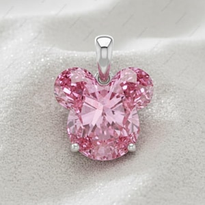 May include: A pink pendant in the shape of a mouse head. The pendant is made of faceted pink gemstones and has a silver bail. The design is a classic and recognizable silhouette, perfect for a necklace.