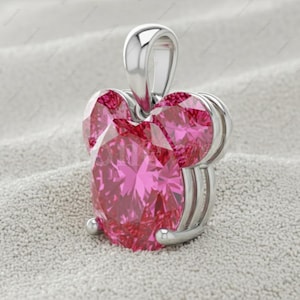 May include: A silver pendant featuring a large, heart-shaped, faceted pink gemstone. The pendant has a loop for a chain and two smaller pink gemstones. The setting is silver, with a polished finish.