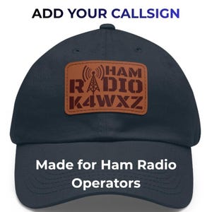 May include: Navy blue baseball cap with a brown leather patch featuring the words "HAM RADIO K4WXZ" and a radio tower graphic. The text "ADD YOUR CALLSIGN" is above the cap, and "Made for Ham Radio Operators" is below.