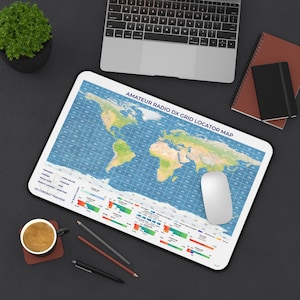 May include: A rectangular mousepad featuring a world map with grid lines and the text "AMATEUR RADIO DX GRID LOCATOR MAP." The map is surrounded by a black border. A white mouse and a laptop are also visible.