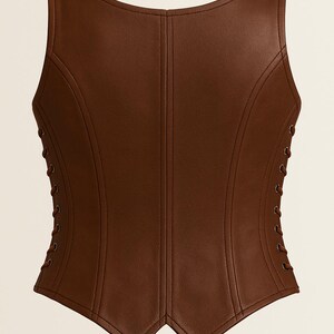 May include: A sleeveless brown corset top featuring a smooth, leather-like finish with vertical seam detailing. The garment includes a scoop neckline and side panels with matching brown lace-up closures, ending in a pointed, V-shaped hemline.