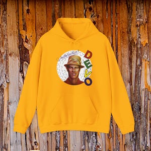 May include: A bright yellow hooded sweatshirt featuring a graphic print of a person wearing a hat inside a white circle. The text "Are We Not Men?" is written in a script font above the person, and the word "DEVO" is printed vertically in colorful letters.