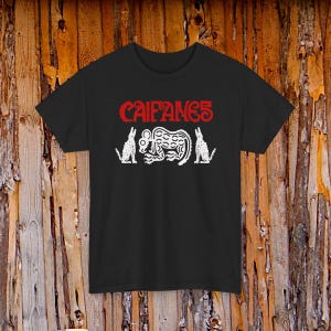 Può includere: Una t-shirt nera a maniche corte con la scritta rossa CAIFANES stampata sopra un'illustrazione grafica bianca di una creatura centrale stilizzata affiancata da due figure animali più piccole su entrambi i lati, centrata sul capo.