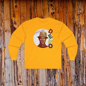 May include: A bright yellow long-sleeve shirt featuring a circular graphic on the chest. The graphic depicts a person wearing a tan hat, with the text "Are We Not Men?" in script and the word "DEVO" in stacked, multi-colored block letters.