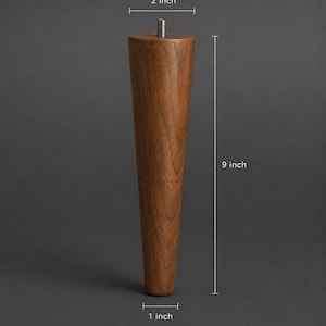 May include: A tapered wooden furniture leg with a natural brown wood grain finish. The leg measures 22.86 cm in height, with a 5.08 cm diameter at the top and a 2.54 cm diameter at the base. It features a metal M8 hanger bolt at the top centre.