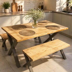 Puede incluir: Una mesa de comedor de madera clara con un banco a juego y un banco más pequeño. La mesa tiene un acabado de vetas de madera natural y patas de metal gris. Cuatro manteles individuales tejidos y un jarrón con flores blancas están sobre la mesa. Los bancos tienen el mismo acabado de madera.