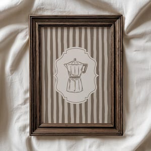 May include: A rectangular dark brown wooden frame containing a print with a vertical beige and brown striped background. Centered on the print is a light beige decorative label shape featuring a detailed line drawing of a moka pot coffee maker.