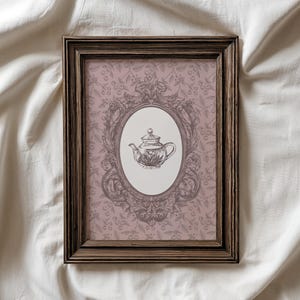 May include: A rectangular dark wood frame containing a print with a dusty pink background featuring a repeating cherry pattern. In the center, an ornate oval frame surrounds a detailed black and white line drawing of a teapot on a white background.
