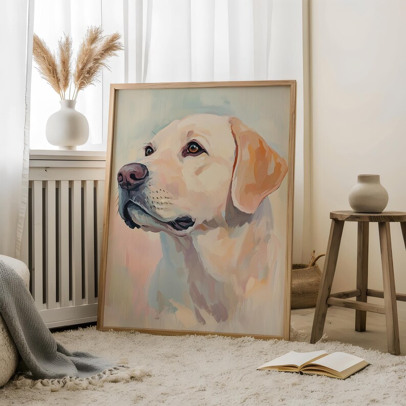 May include: A framed watercolor painting of a yellow Labrador Retriever dog. The dog is depicted in profile, with a soft, pastel color palette. The artwork is displayed in a light-colored wooden frame, leaning against a wall.