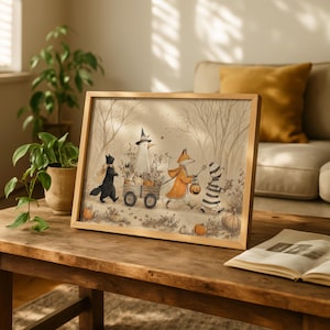 May include: A framed illustration in a light wood frame depicting a black cat, a bird in a witch hat, a fox in an orange cloak, and a striped figure pulling a wooden wagon filled with pumpkins through a forest with bare trees and fallen leaves.