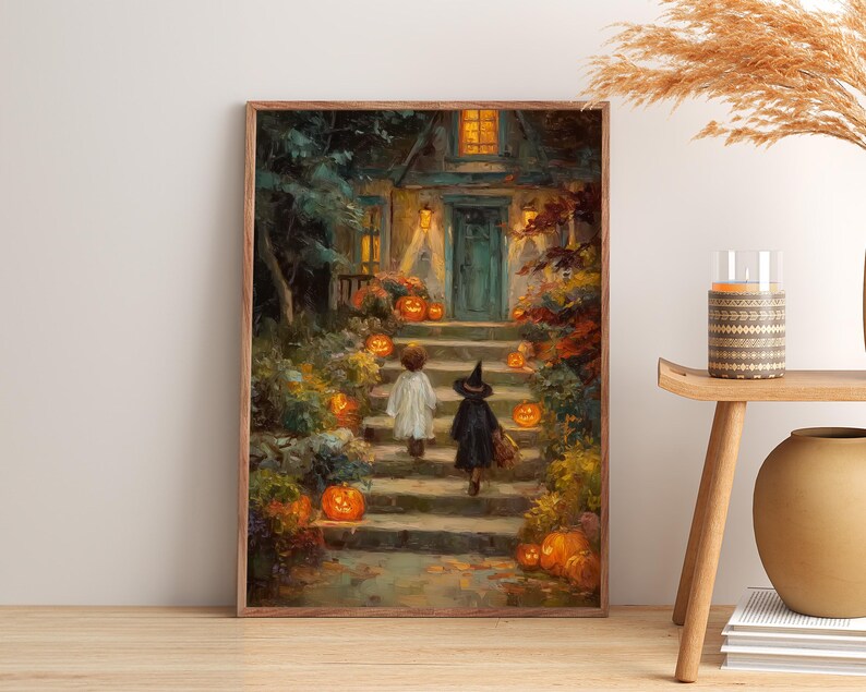 May include: A framed wall art print depicting a nighttime scene of two children in costumes walking up stone steps toward a house entrance. The path is lined with glowing orange pumpkins, autumn foliage, and warm yellow light from the house windows.