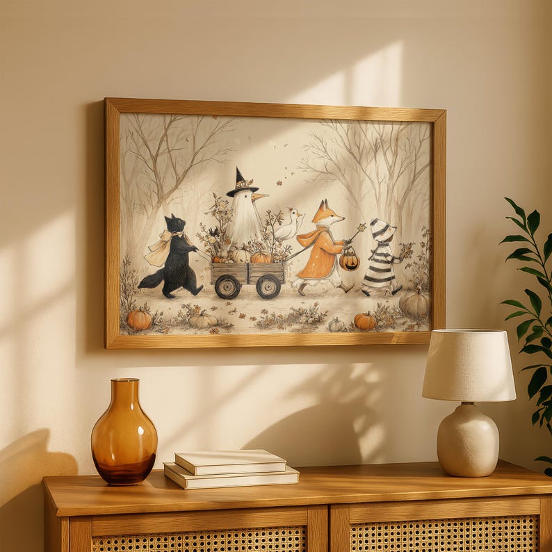 May include: A framed wall art print featuring a whimsical autumn scene with a black cat, a bird in a witch hat, a fox in an orange coat, and a striped creature pulling a wooden wagon filled with pumpkins through a forest of bare trees.