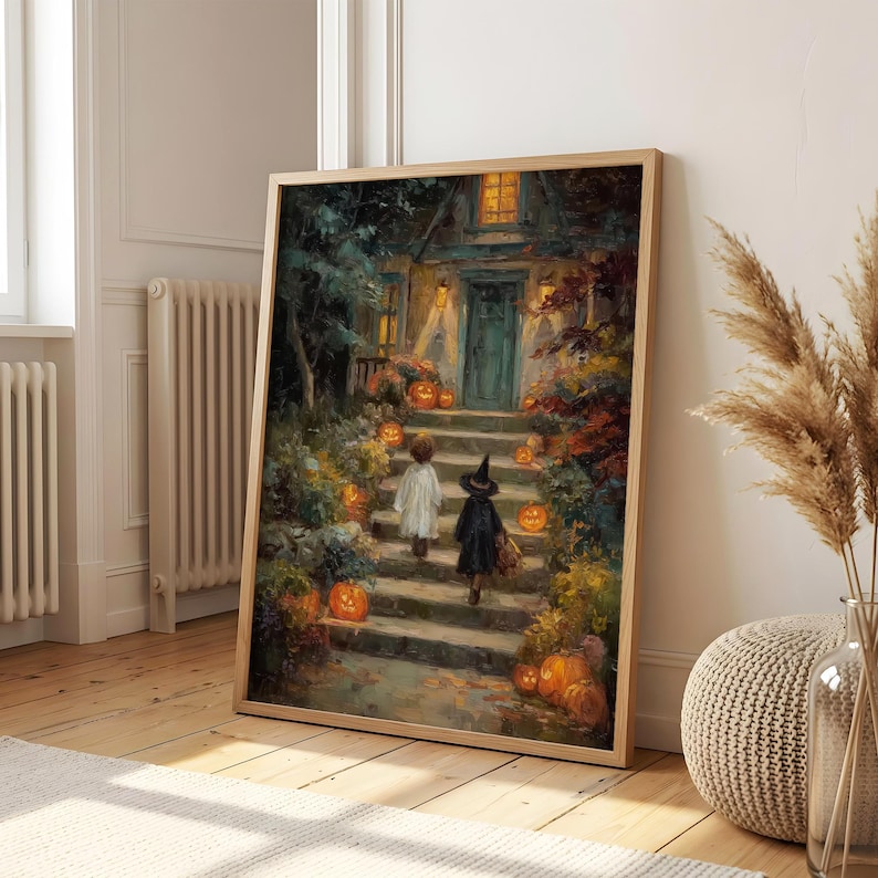 May include: A framed wall art print depicting a dark, painterly scene of two children in costumes walking up stone steps toward a house entrance at night, surrounded by glowing orange jack-o'-lanterns, autumn foliage, and warm golden light.