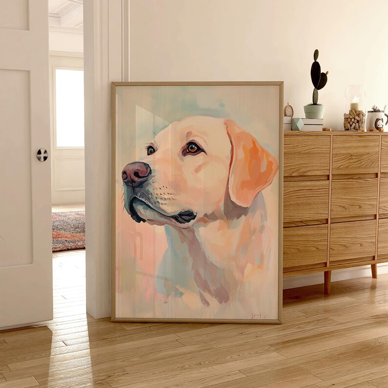 May include: A framed watercolor painting of a yellow Labrador Retriever dog. The dog's head is turned to the side, with a pink nose and light brown eyes. The background has soft pastel colors of pink, blue, and yellow.