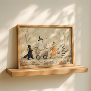 May include: A framed horizontal print featuring a whimsical illustration of a black cat, a white bird in a witch hat, a fox in an orange coat, and a striped figure pulling a wooden wagon filled with pumpkins through a forest of bare trees.
