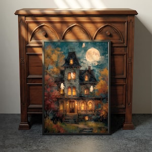 May include: A framed wall art print depicting a multi-story house at night with glowing yellow windows, surrounded by autumn trees in shades of orange and yellow, under a large full moon with several small white ghost figures floating nearby.
