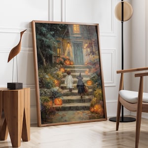 May include: A framed rectangular wall art print depicting a nighttime scene of two children in costumes walking up stone steps toward a house illuminated by warm glowing jack-o'-lanterns and porch lights, surrounded by autumn foliage and trees.