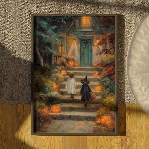 May include: A framed art print depicting a house entrance at night with two figures walking up stone steps. One figure wears a white ghost costume, the other a black witch costume. Numerous glowing orange pumpkins are placed along the stairs.