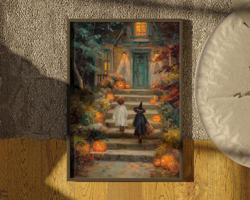 May include: A framed art print depicting a house entrance at night with two figures walking up stone steps. One figure wears a white ghost costume, the other a black witch costume. Numerous glowing orange pumpkins are placed along the stairs.