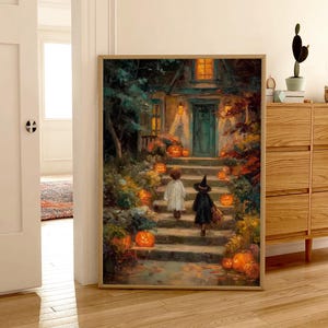 May include: A framed wall art print depicting a nighttime scene of two children in costumes walking up stone steps toward a house entrance. The path is lined with glowing orange pumpkins, lush foliage, and warm light emanating from the home windows.