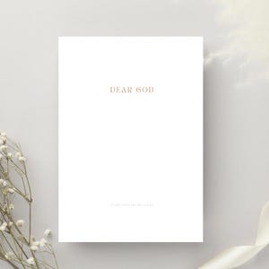 Könnte beinhalten: Eine weiße Karte mit dem Text "DEAR GOD" in goldfarbener Schrift. Darunter steht in kleinerer Schrift "START YOUR DAY WITH GOD". Die Karte befindet sich vor einem weichen, neutralen Hintergrund mit floralen Akzenten.