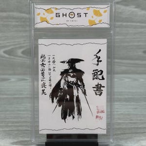 Puede incluir: Una tarjeta calificada con ilustraciones de "Ghost of Tsushima". La tarjeta muestra una ilustración en blanco y negro de un samurái con dos espadas, junto con texto japonés. La parte superior de la tarjeta tiene el logotipo del juego y un diseño de hojas de ginkgo.