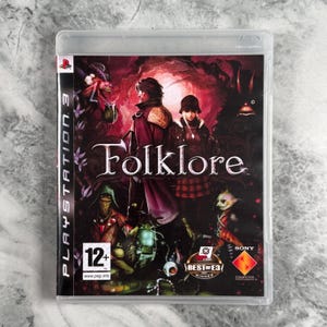 Op de afbeelding: Een PlayStation 3 videogamehoesje voor de titel Folklore. De cover toont twee centrale figuren in donkere kleding, omringd door diverse fantastische wezens tegen een dieprode en zwarte achtergrond met het PEGI 12+ classificatielogo.
