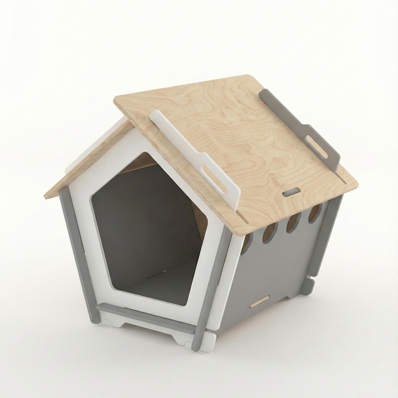 May include: A modern dog house with a pentagon-shaped entrance. The house features a light wood roof, gray and white accents, and a gray interior. The design includes ventilation holes and handles for easy transport.