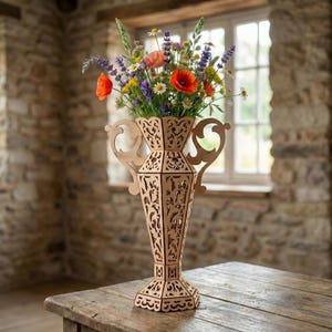 Op de afbeelding: Een houten vaas met ingewikkelde uitgesneden ontwerpen, met een levendig boeket wilde bloemen. De vaas heeft een unieke vorm met handvatten en staat op een houten tafel. De bloemen omvatten oranje klaprozen, madeliefjes en lavendel.